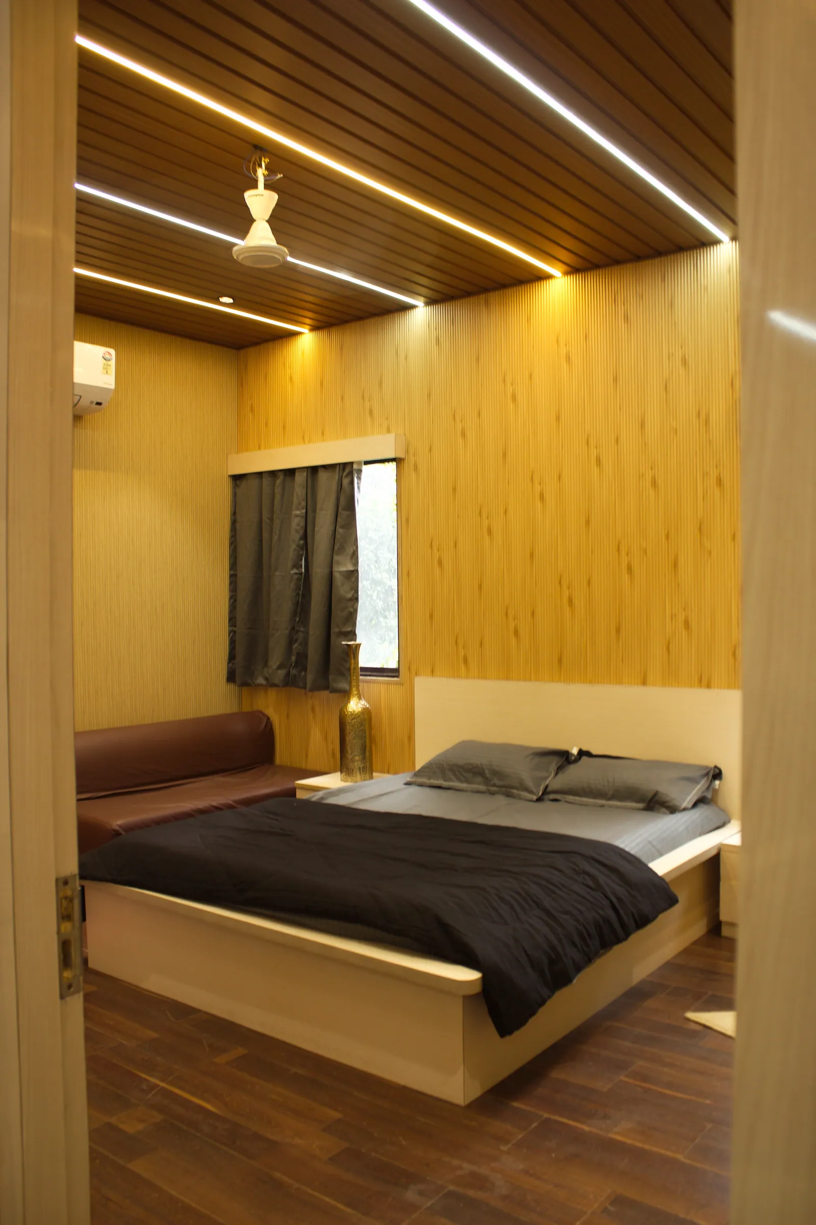 A bedroom at Raj Organic Farm with a wood-slat ceiling, light strips and a double bed seen from the doorway
