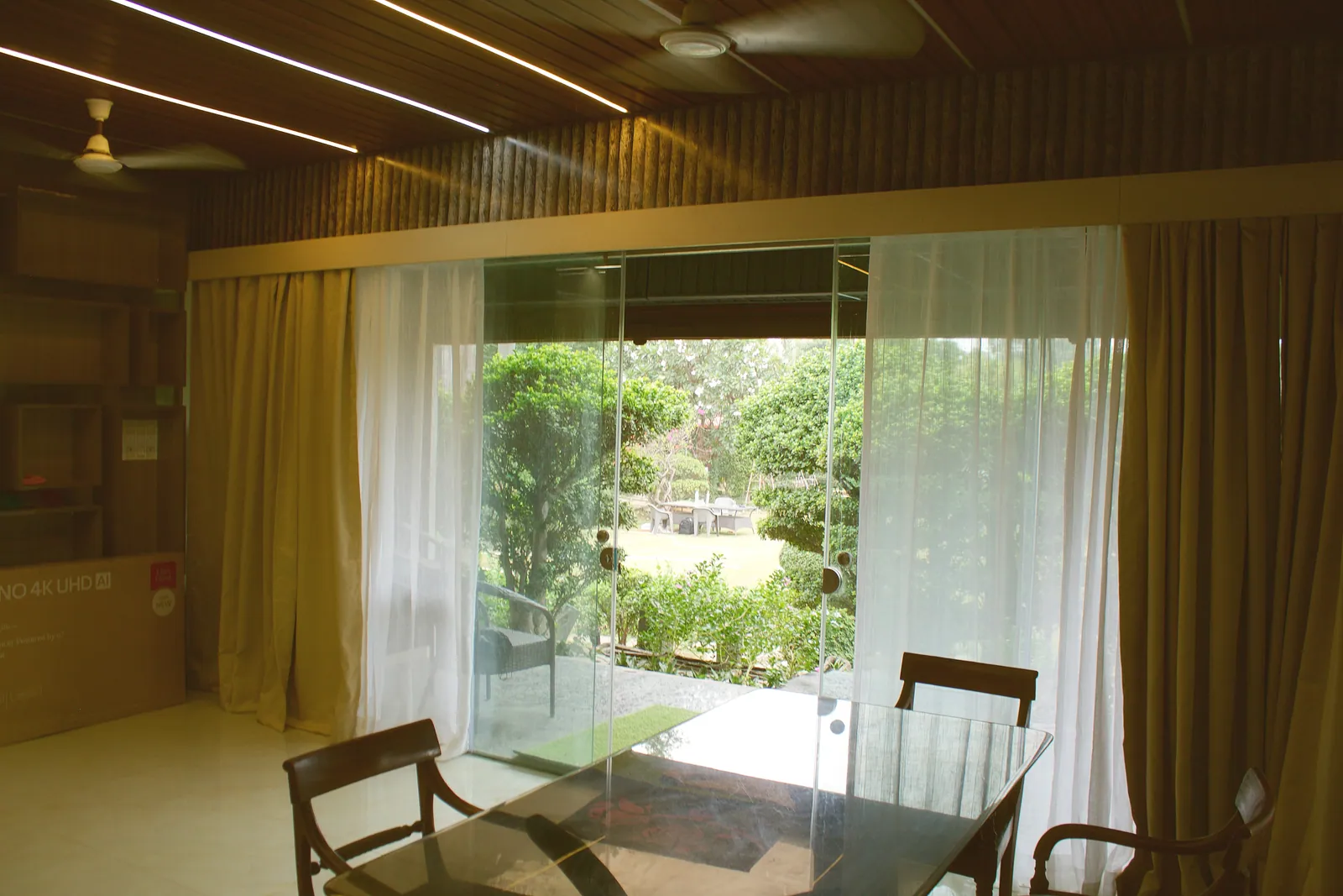 A glass dining table by the sliding glass wall with a view of the garden at Raj Organic Farm